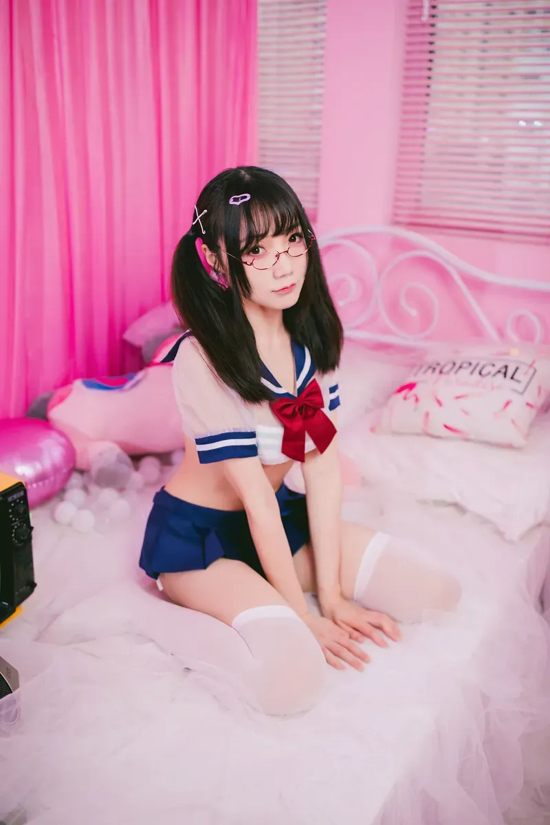 cosplay摄影系列归档 人物穿着蓝白校园风服装坐在粉色室内空间中的照片