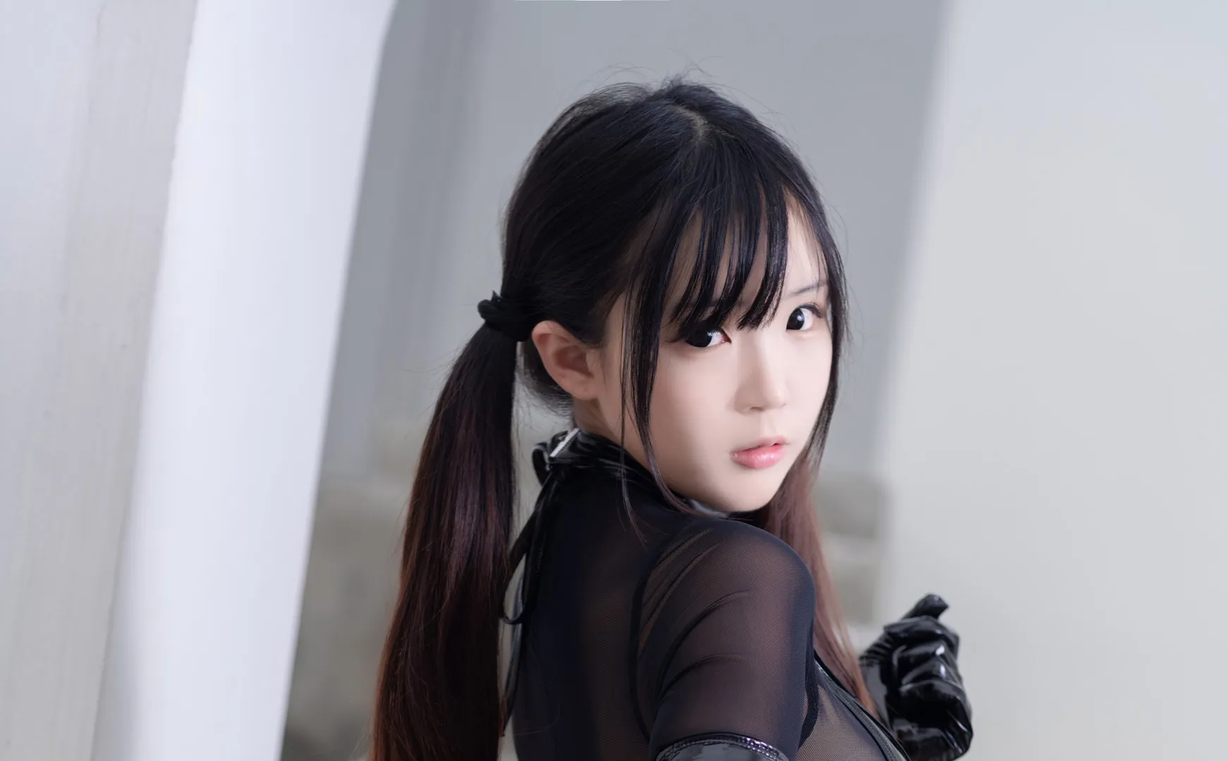 摄影线索阶段性整理 黑色双马尾发型与深色服装造型，浅色拱形建筑背景，人物回头看向镜头的近景摄影