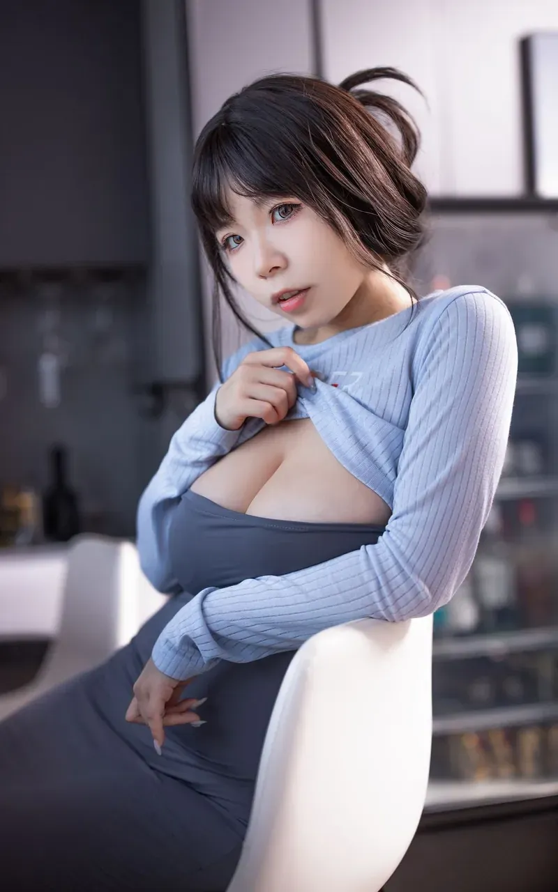 无颜小天使wy身穿浅蓝色长袖上衣和深灰色紧身裙，坐在椅子上，眼神看向镜头