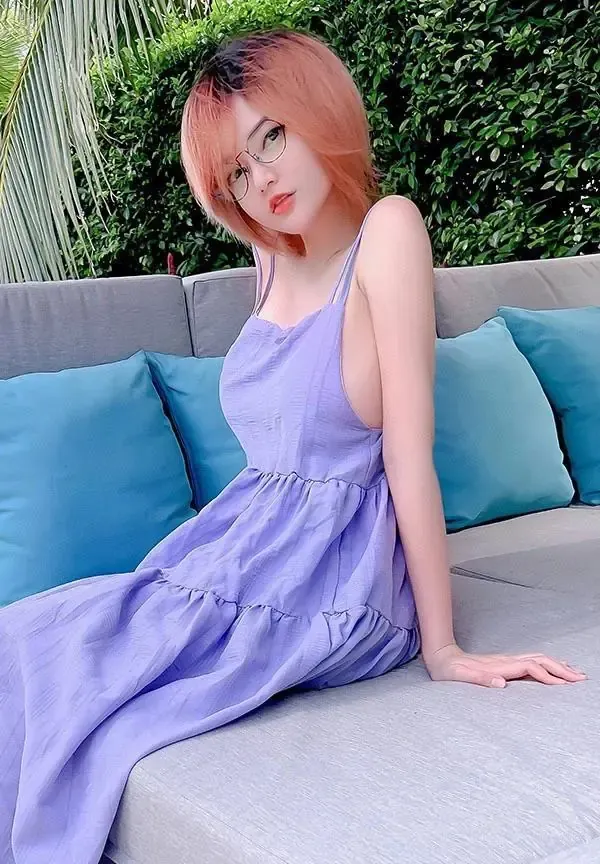 星野saori佩戴黑框眼镜与浅棕短发在庭院沙发侧坐身穿浅紫吊带长裙