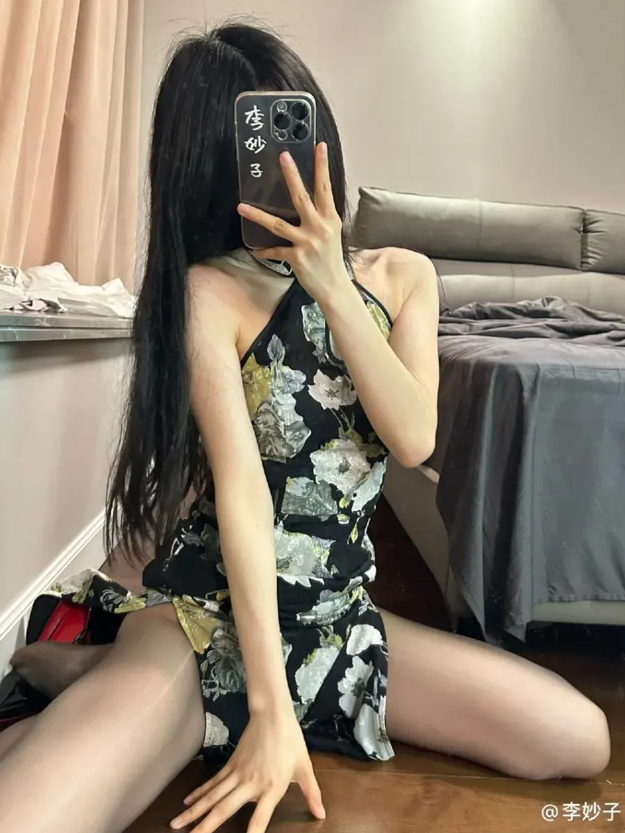 李妙子身着黑底碎花挂脖旗袍跪坐在木地板上对镜自拍