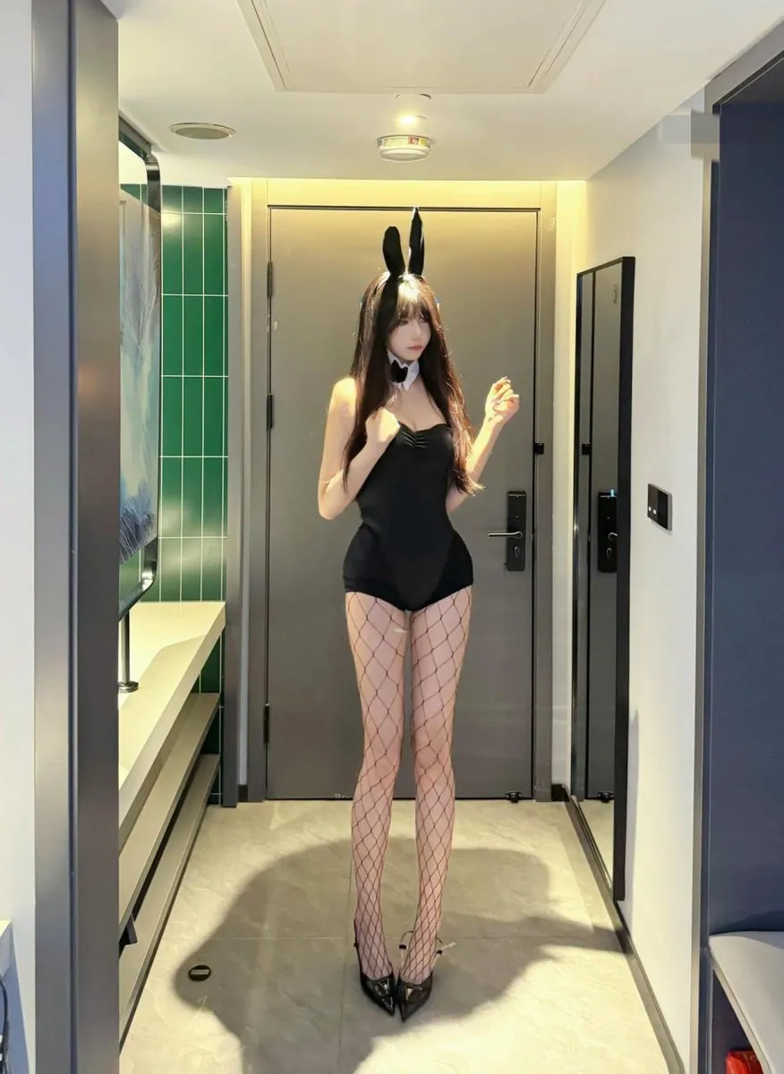 抖音神明同同头戴黑色兔耳发箍身穿黑色连体衣搭配网袜站在玄关走廊